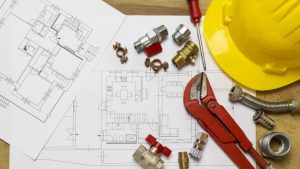 How To Write A Resume For Plumbers - large plumbing blueprint on a work table with tools and a hard hat next to it.