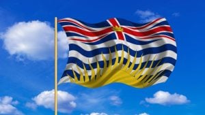 Minimum Wage in British Columbia In 2024 - the BC flag against a bright sky.